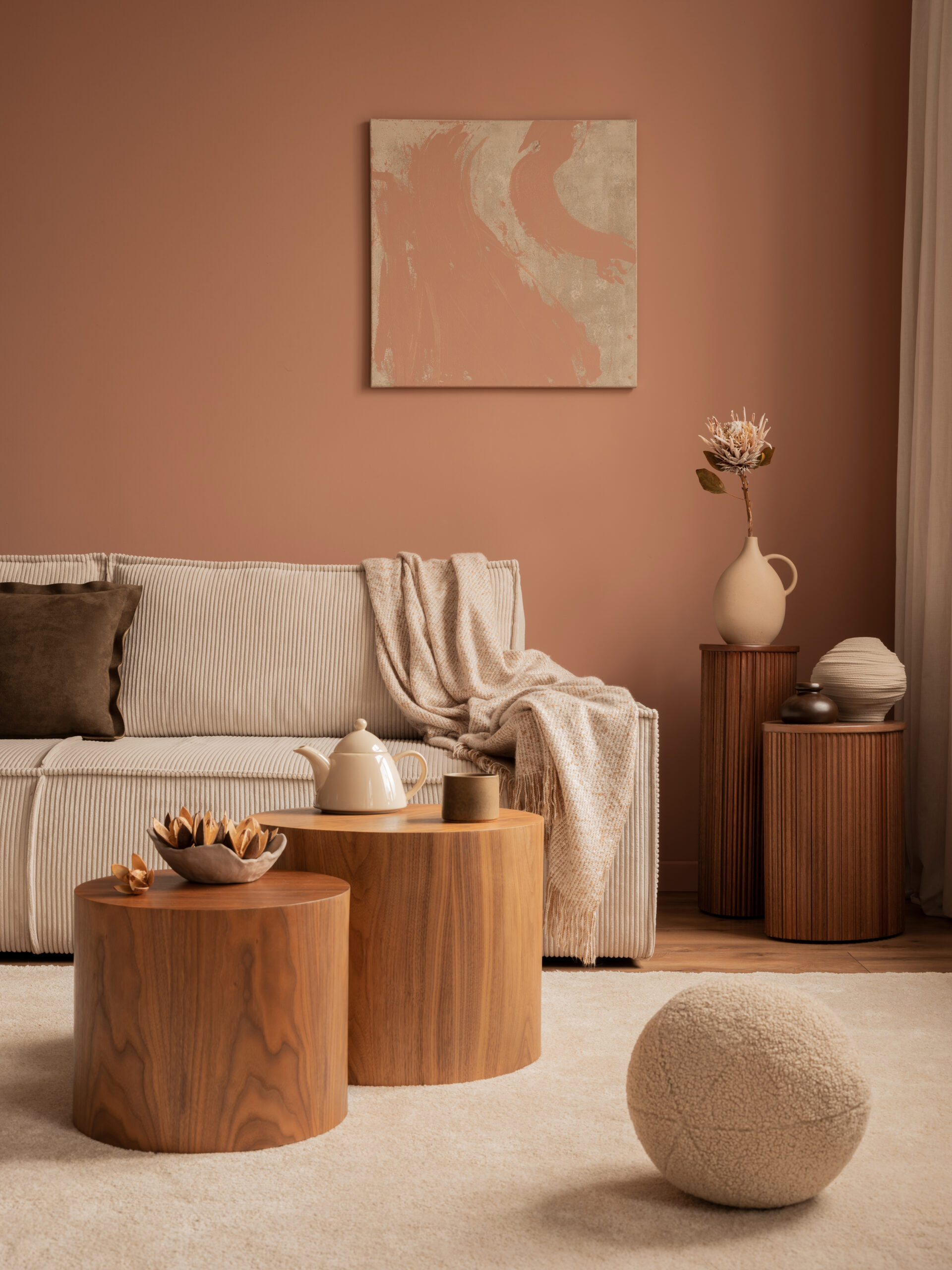 Warm and cozy living room interior with mock up poster frame, modular sofa, round wooden coffee table, pitcher, plaid, vase with dried flower, pillow and personal accessories. Home decor. Template.